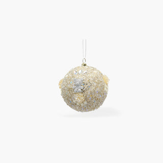 Bola de Natal coberta de lantejoulas, contas e flores em tons de prata e creme, com um pequeno urso prateado e fio transparente