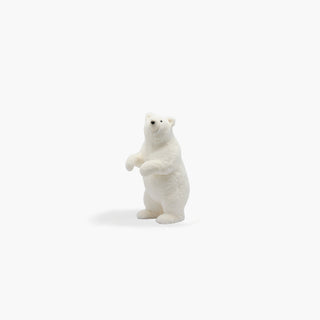 Cria de Urso polar branco de pelo felpudo, em pé sobre as patas traseiras, com as patas dianteiras junto ao peito, sobre fundo cinzento claro