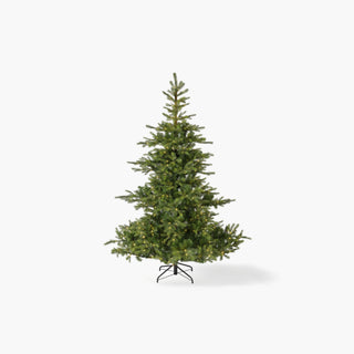 Pinheiro de Natal artificial verde e frondosa, com pequenas luzes quentes entre os ramos e base em metal, sobre fundo branco