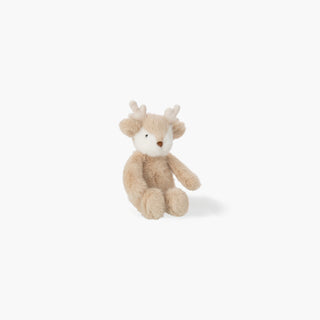 Rena de peluche bege com focinho branco, pequenos cornos claros e pelo felpudo, sentada sobre fundo branco