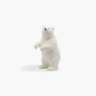 Urso polar branco de pelo felpudo, em pé sobre as patas traseiras, com as patas dianteiras junto ao peito, sobre fundo cinzento claro