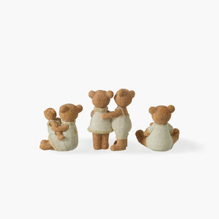 Três cenas de ursos castanhos com roupas de malha creme e estrelas douradas: mãe com cria ao colo, casal abraçado e pai com cria sentada